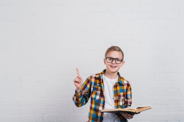 portrait smiling boy with eyeglasses holding open book hand pointing his finger upward 23 2148088995 1